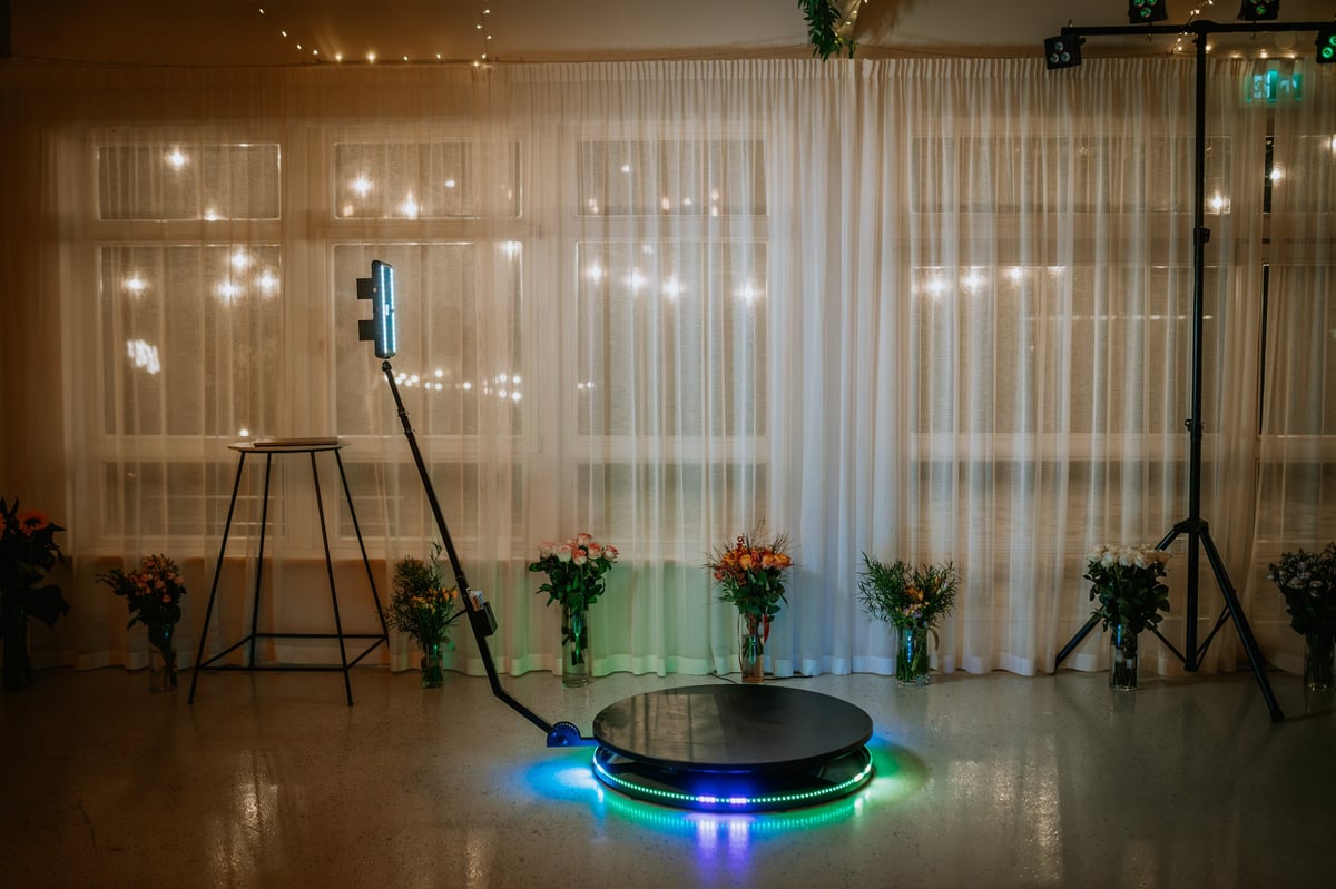 360-degree photo booth setup with LED lights and floral arrangements
